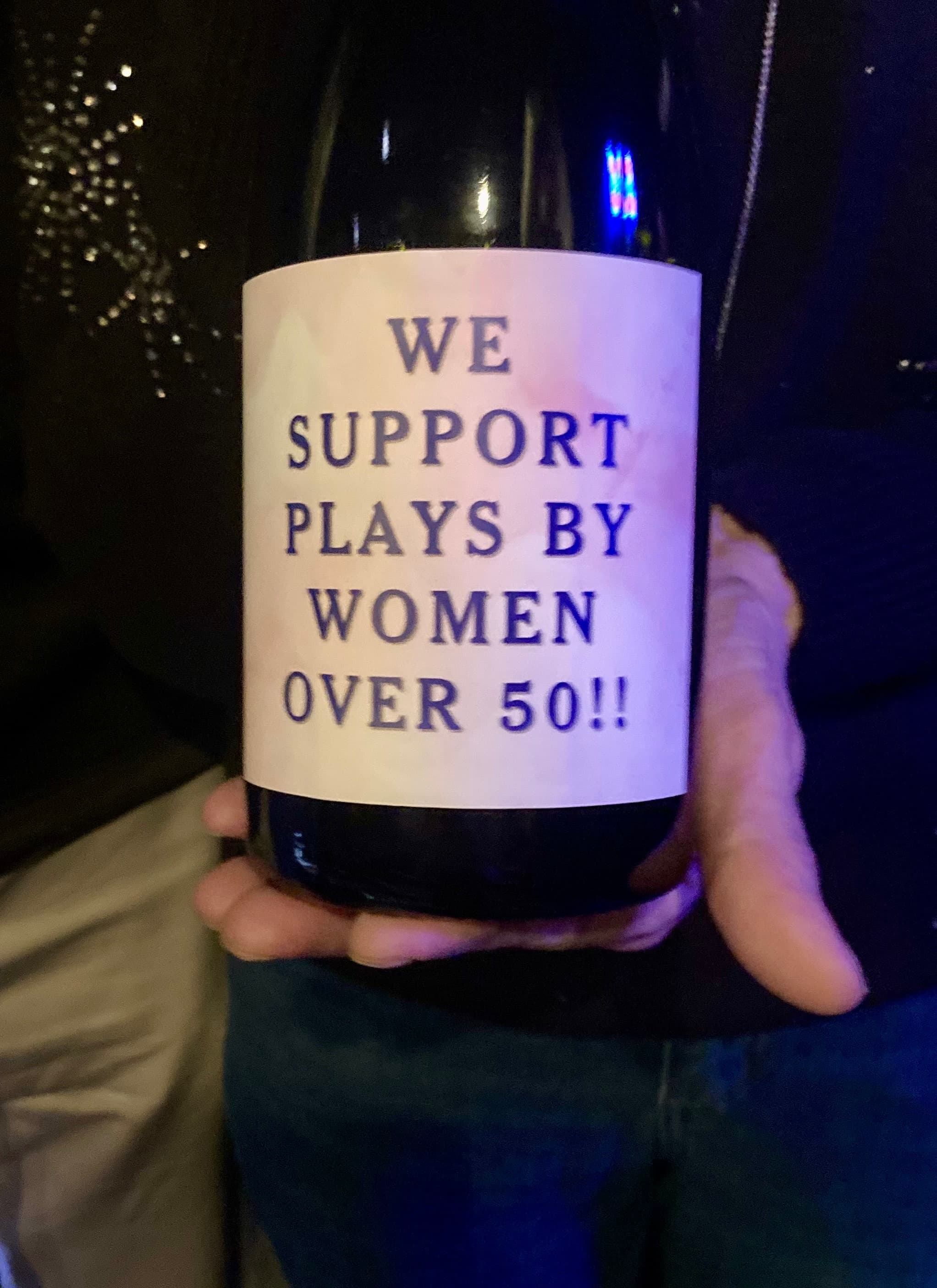 The "We Produce Plays by Women Over 50" bubbly bottle